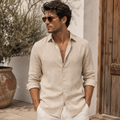 Model wearing men's relaxed beige linen shirt in Mediterranean villa courtyard - Rivaro