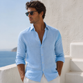 Model wearing men's sky blue linen shirt with sunglasses overlooking the sea - Rivaro